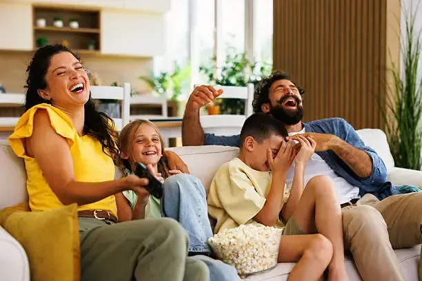 Happy family laughing together while watching IPTV content on a large screen TV