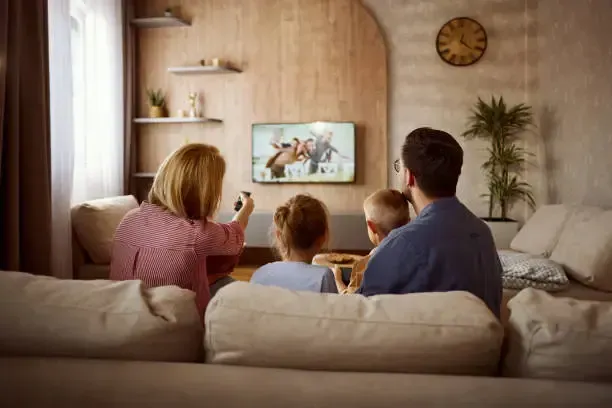 Family watching live sports and movies on IPTV service from the sofa