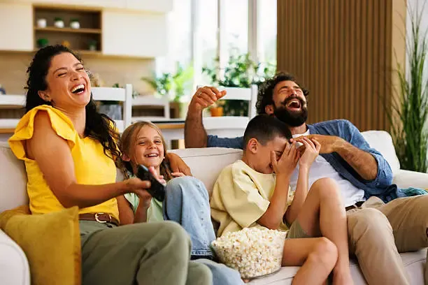 Happy family laughing together while watching IPTV content on the sofa